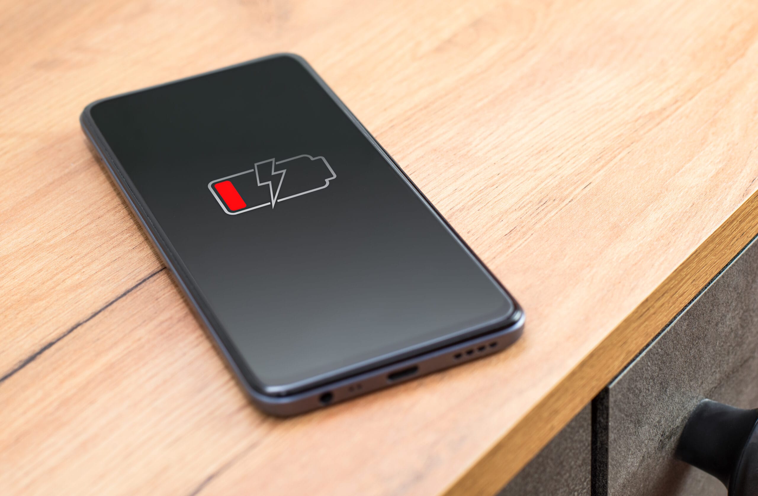 discharged smartphone on the table. phone with low charged battery screen